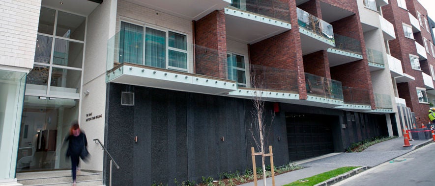 Woman enters the main door of a modern Auckland apartment block.