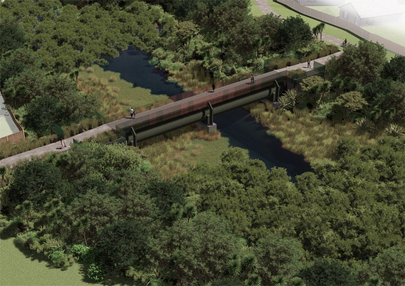 People walking over the foot bridge over Harania Creek with bush on both sides. 