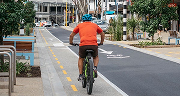 A man rides a bicycle along a cycle lane developed as part of the Hurstmere Road transformation.