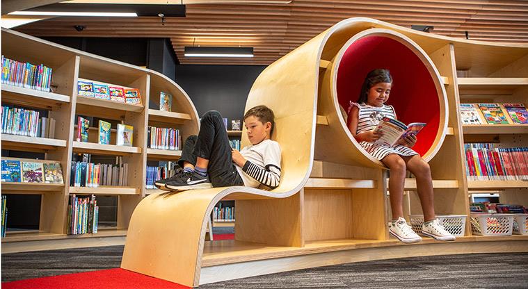 Children reading on library furniture.