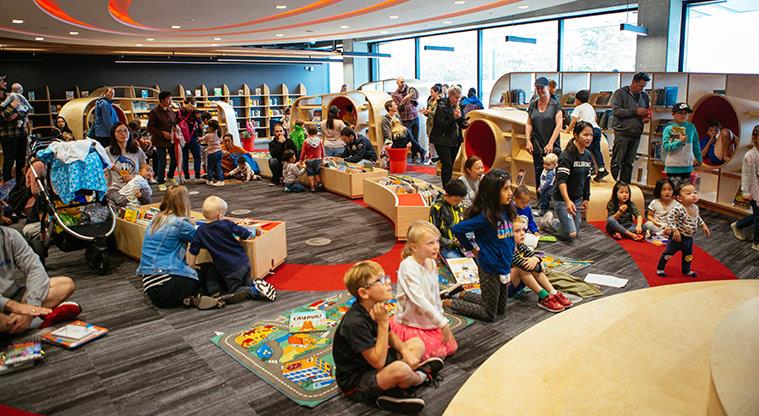 Children and parents in an activity space, with some looking at something outside the frame.