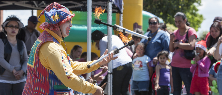 A crowd watches a person juggling flaming batons.