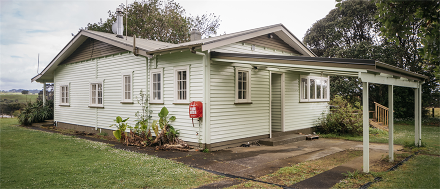 A vehicle shelter attached to a detached house, with all four sides open.