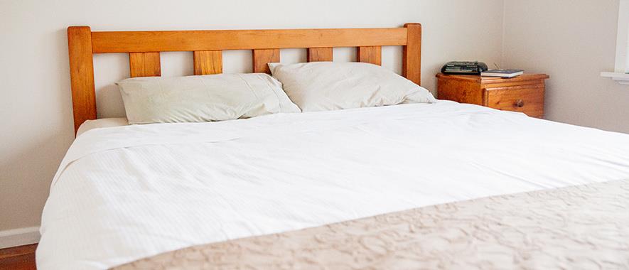 Bed with side-table and alarm clock.