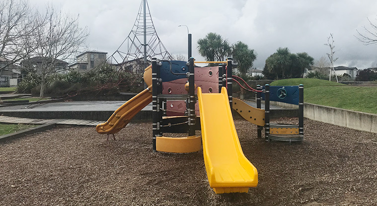 Barry Curtis Park - Colourful junior play module with slides, steps, ramps and high climbing nets in the background.