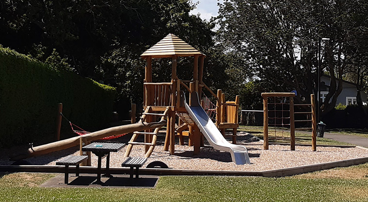 Centennial Park - Playground with climbing nets and ladders, wobbly bridge and slide, and a picnic table in the foreground.