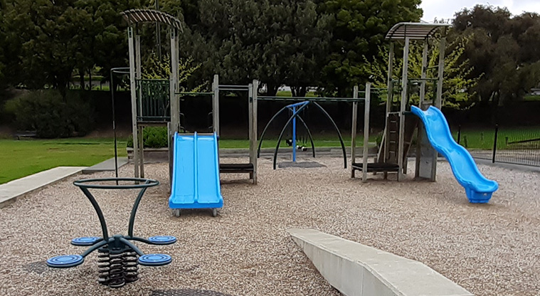 Glover Park - Climbing towers with slides at different heights and a spinning rocker, with swings in the background.