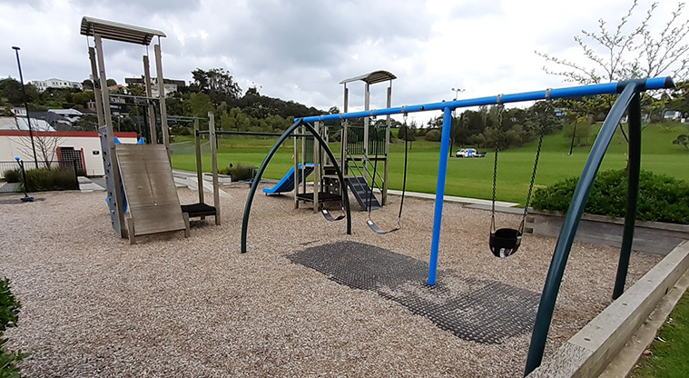 Glover Park - Set of three swings with the play towers and climbing wall in the background.