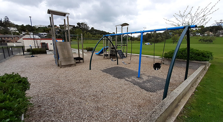 Glover Park - Whole playground showing the swing set and the play towers with the toilets and changing rooms in the background, and the sports fields to the right.