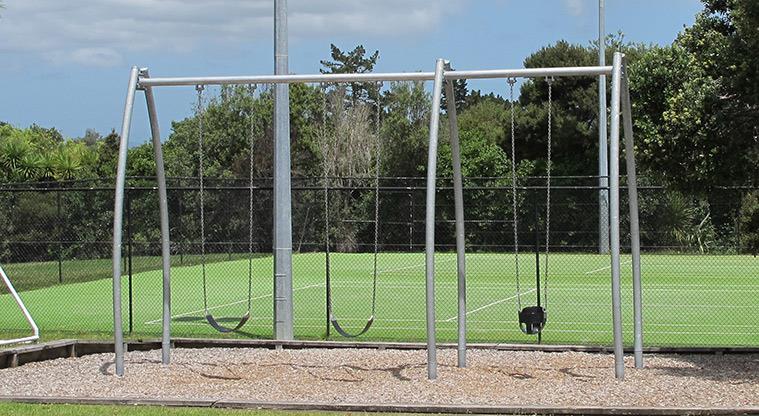 Greenhithe War Memorial Park - Set of three swings with the tennis courts in the background.
