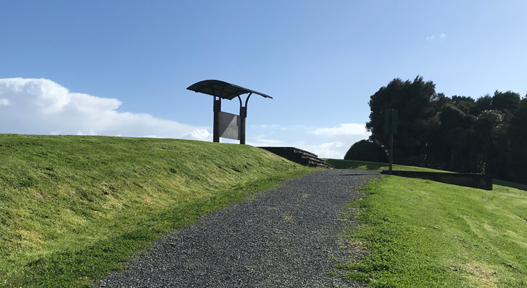 Harbourview - Orangihina Park - Section of gravel track going uphill towards a park information board.