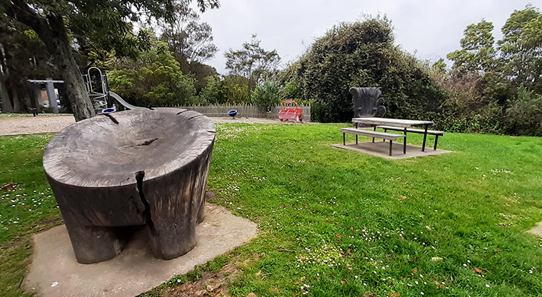 Kell Park - Large tree stump and picnic table with the playground in the background.