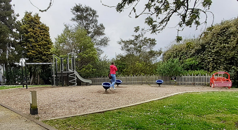 Kell Park - Playground with spinning egg seats, play car, monkey bars, and a climbing structure with slide and twisted poles.