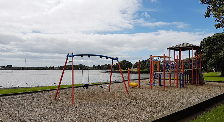 Kiwi Esplanade - Playground with climbing equipment and a set of two swings with a view across the harbour.
