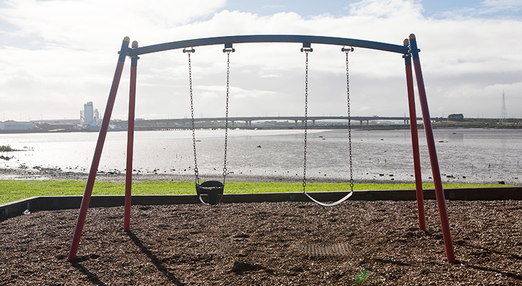 Kiwi Esplanade - Set of two swings with a view across the harbour towards Māngere Bridge.