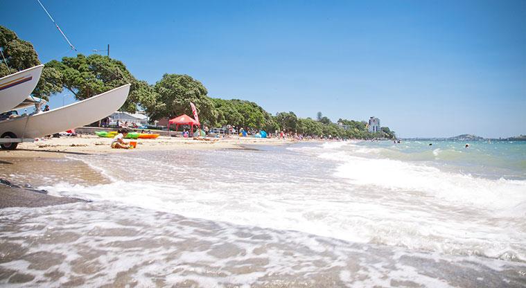 Kohimarama Beach Reserve - Section of the beach with boats on the sand, and trees in the background.