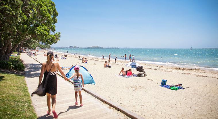 Kohimarama Beach Reserve - Section of the beach with people walking along the boardwalk.