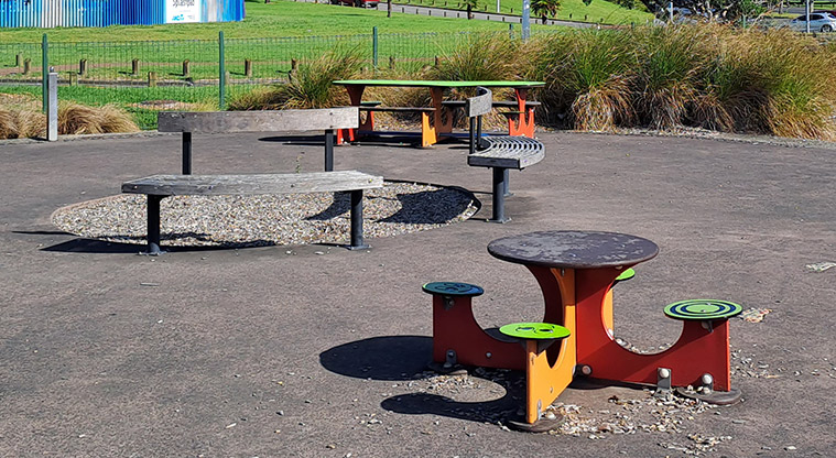 Lloyd Elsmore Park - Colourful tables and bench seats inside the playground area. Photo credit: S Hulse.