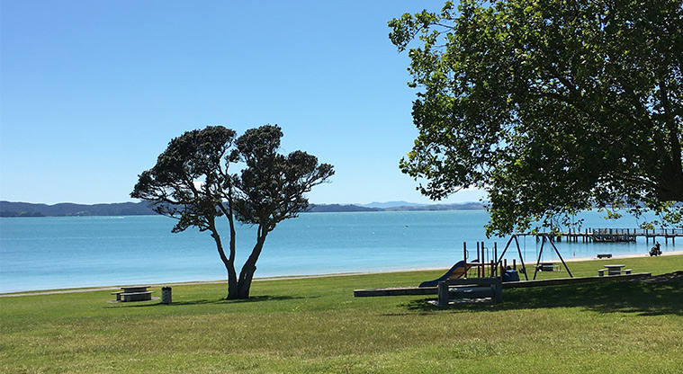 Maraetai Park - Looking out to sea with the preschool playground, trees and wharf in the background. Photo credit: S Hulse.