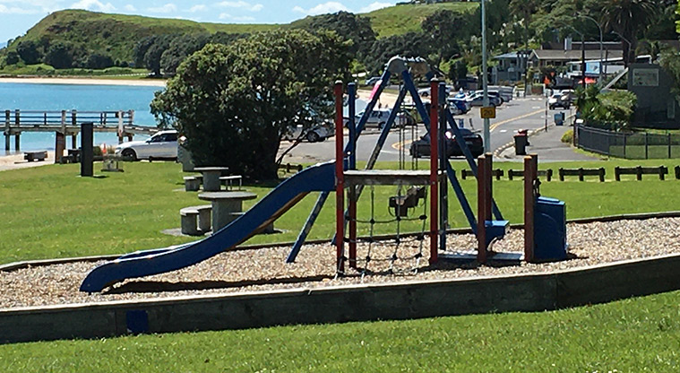Maraetai Park - Preschool playground with a set of two swings, a climbing net and wide slide. Photo credit: S Hulse.