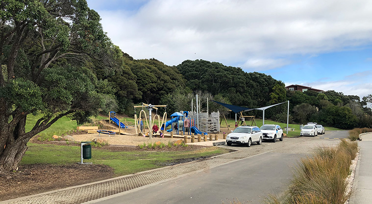Omana Esplanade - Roadside parking with the playground and large trees in the background.