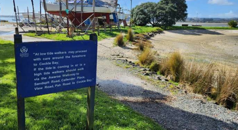 Pōhutukawa Avenue Esplanade Reserve - Walking path with a sign board.