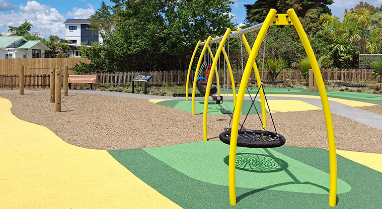 Rānui Domain - The swing set (including basket swing) with the balance rope course, bench seat, information board and hammocks in the background.