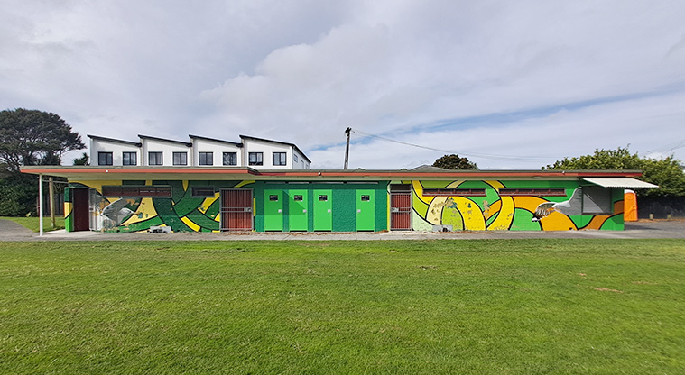 Rānui Domain - Front view of the toilets and changing rooms with part of the sports field in the foreground.