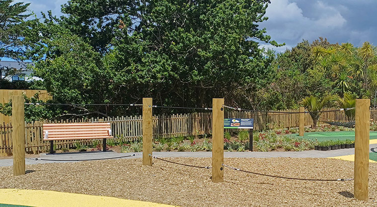 Rānui Domain - Balance rope course with a bench seat, path and information board in the background.
