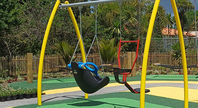Rānui Domain - The inclusive swings with a section of the garden and fence in the background.