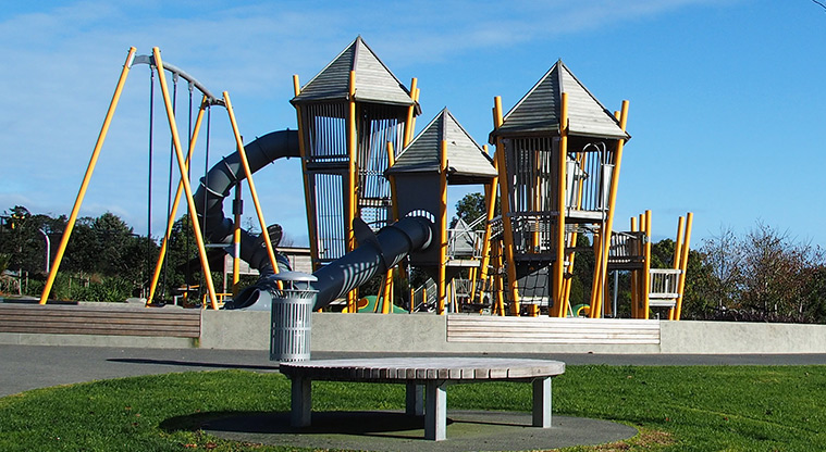 Royal Reserve - Round wooden slat seat with the playground in the background. Photo credit: Tracey Hodder.