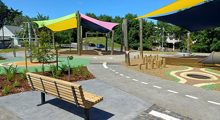 Shepherds Park – Bench seat with parts of the playground under shade sails in the background.