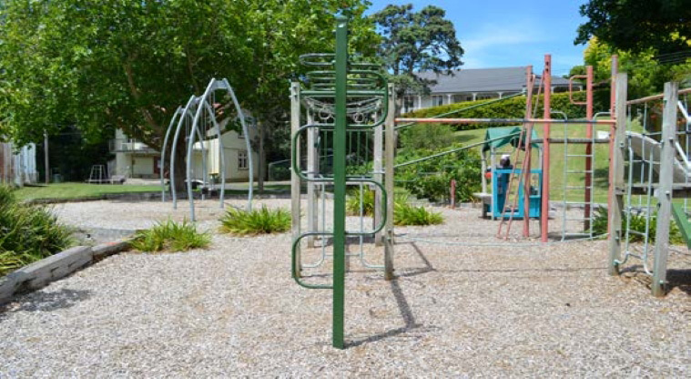 Stanley Bay Park - Playground with climbing equipment, toddler play unit, with the swings and trees in the background.