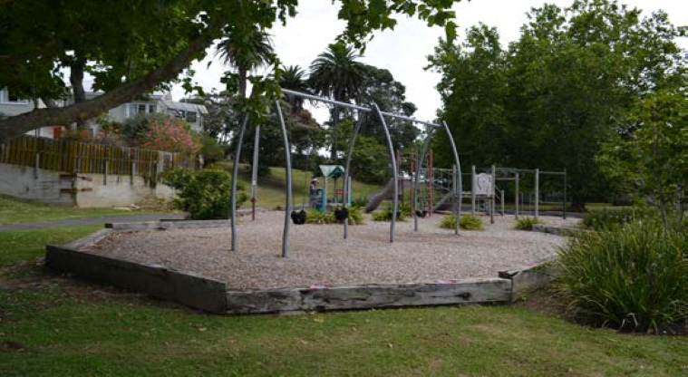 Stanley Bay Park - Swing set with the rest of the playground and trees in the background.
