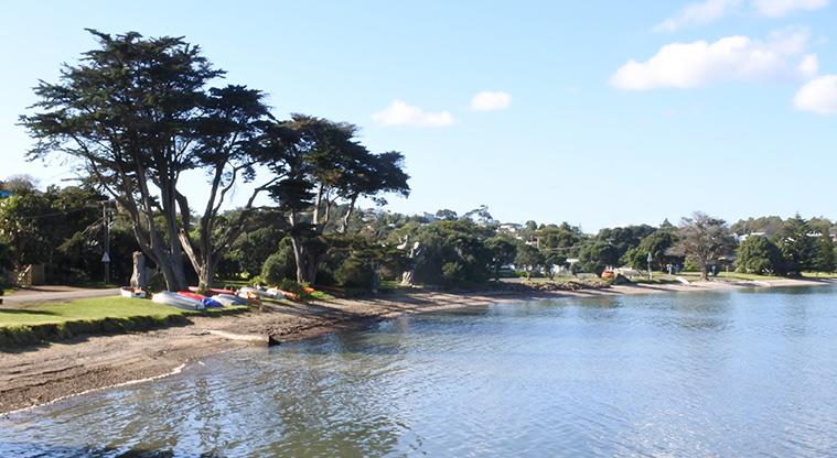 Surfdale Hall Reserve and Foreshore - Section of the beach with trees and dinghies in the background.