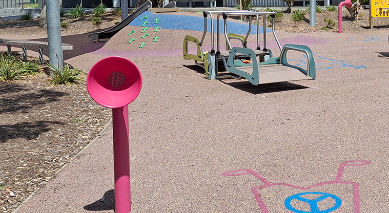 Takapuna Beach Reserve - A bright pink talking tube with the wheelchair accessible seesaw in the background.