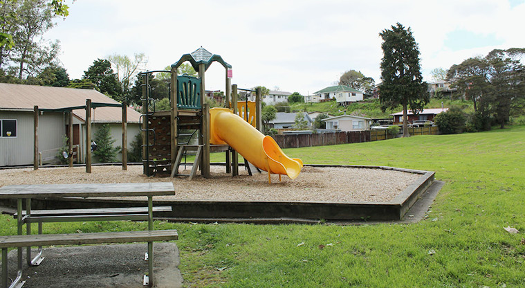 Tūī Glen Reserve - Small play module for younger children with climbing wall, platforms, two yellow slides, and two swings.