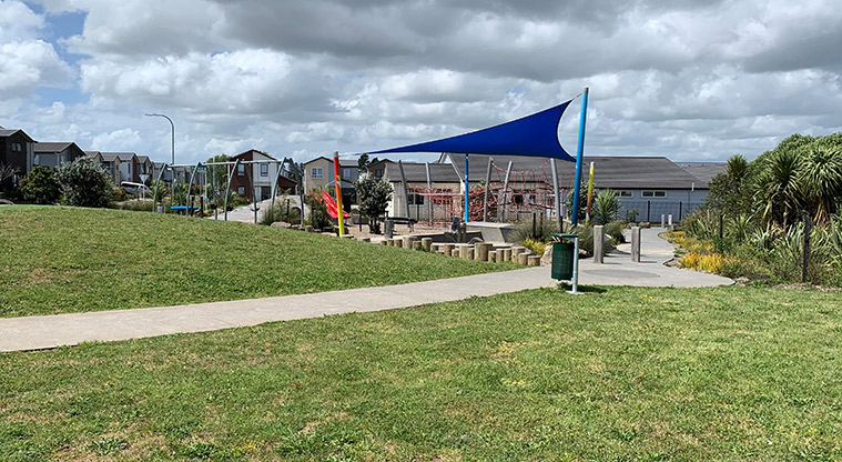 Waimāhia-ki-uta / Waimahia Park - Open grassed space with a section of the playground in the background.