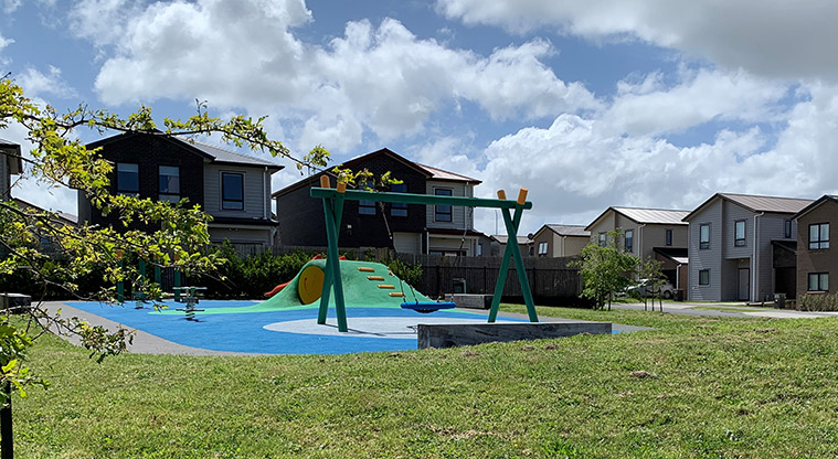 Waimāhia-ki-uta / Waimahia Park - Section of the playground with a standalone basket swing, and a climbing mound and tunnel in the background.