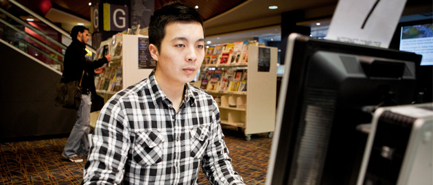 A young man using a computer in a library.